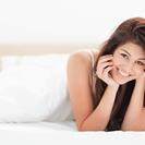 禾大品牌女性与深色头发躺在她前面微笑的床上