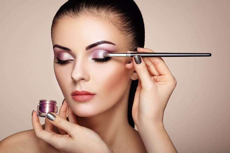 使用化妆刷涂抹紫色闪光眼影的女性，展示Croda的Moonshine效果颜料系列
